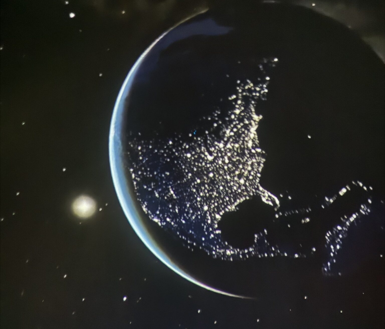 Earth’s crescent and city lights projected across the planetarium dome — the kind of view campers get inside.