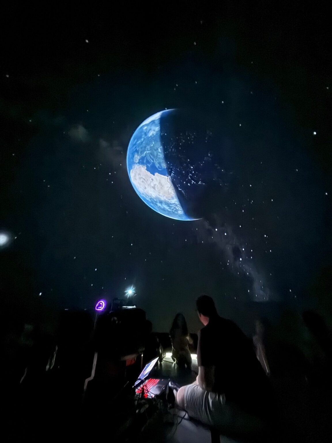 Earth and the moon projected inside the planetarium dome — the kind of perspective students see during a session.