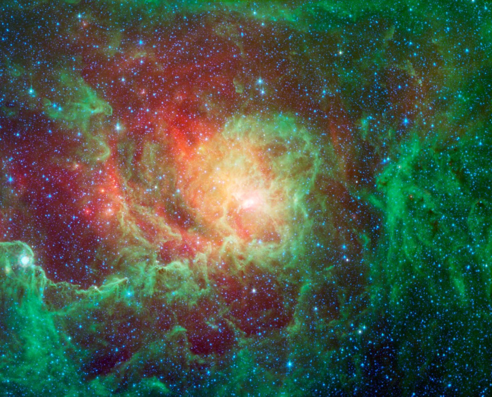 The Lagoon Nebula: glowing clouds of green and orange dust dotted with newborn stars across a deep blue star field, imaged by NASA’s Spitzer Space Telescope.